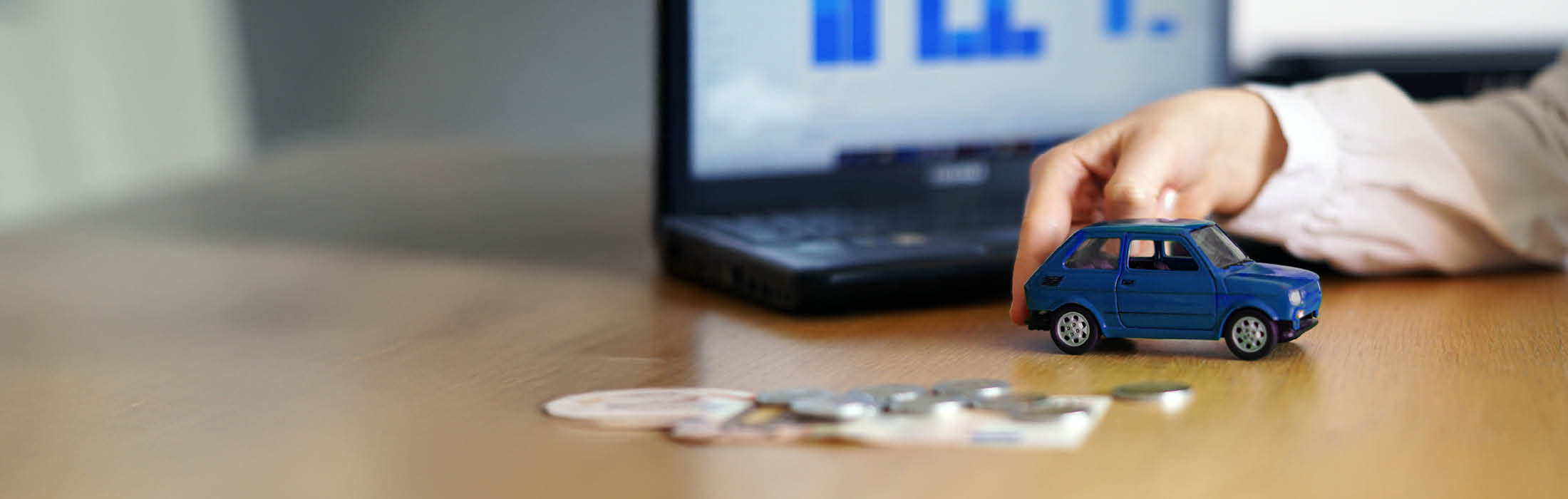 Das blaue Spielfahrzeug und das Geld liegen auf dem Tisch.